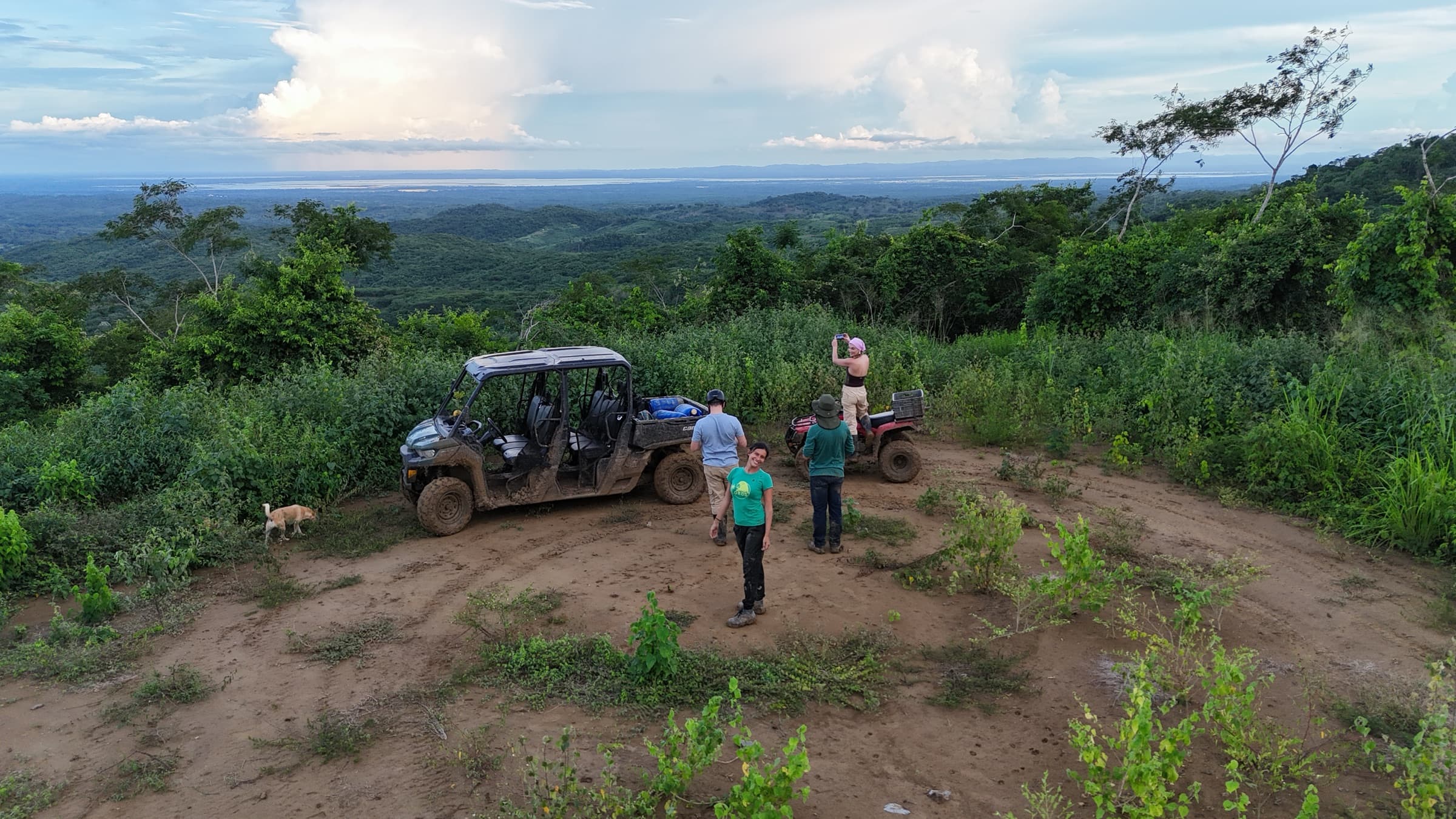 Visitantes y personal del santuario con un UTV y un ATV en una loma, con vista al bosque seco tropical y una laguna a lo lejos cerca de Cartagena